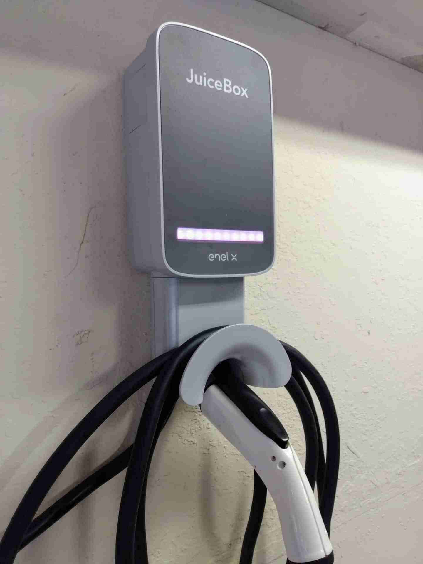 Electric vehicle charging station "JuiceBox" with cable and connector on a wall mount.
