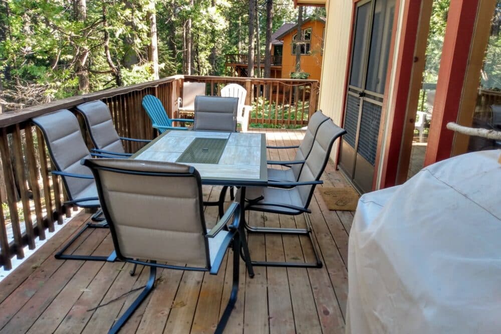 Dorrington Vacation Rental Cabins - Family-friendly deck in the woods with table and chairs.
