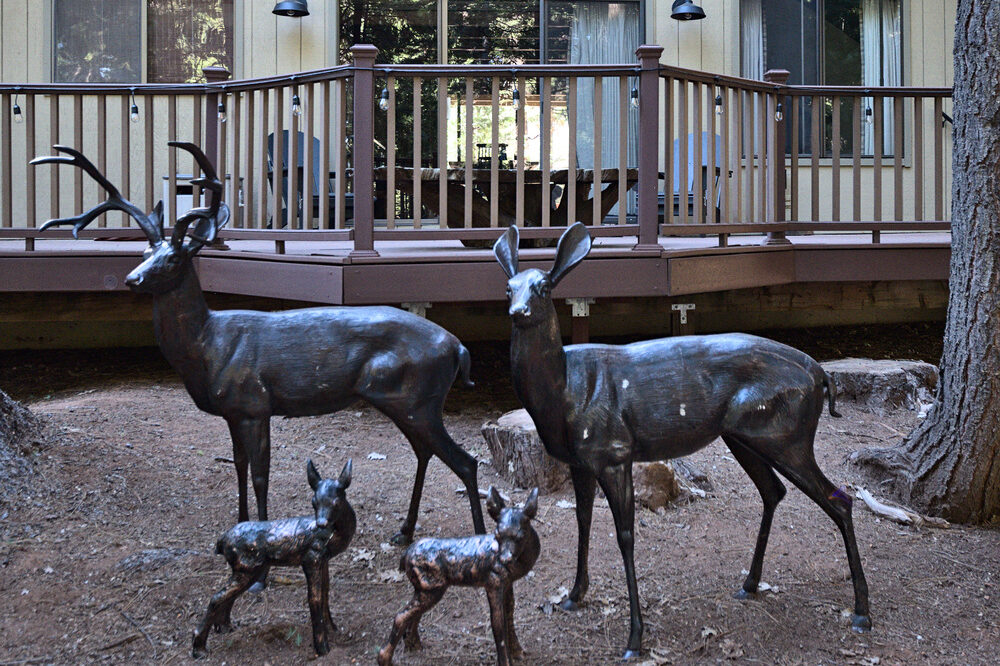 Dorrington Vacation Rental Cabins - A group of deer statues in front of a cottage.