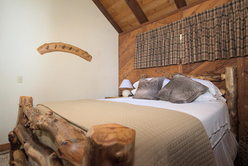 Dorrington Vacation Rental Cabins - A wooden headboard in Evergreen Pinecone Cottage.