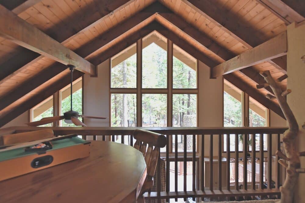 Dorrington Vacation Rental Cabins - The attic of a cabin with wooden beams and a table in Evergreen Cottage.
