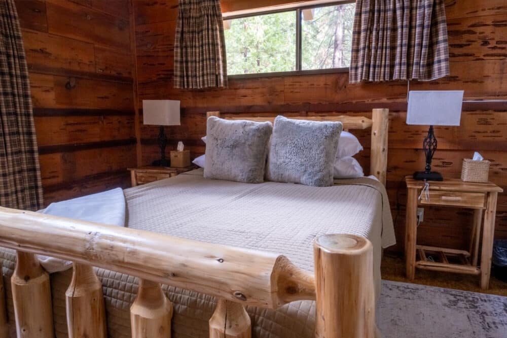 Dorrington Vacation Rental Cabins - A cozy bedroom in an Evergreen log cabin with a bed and pillows.