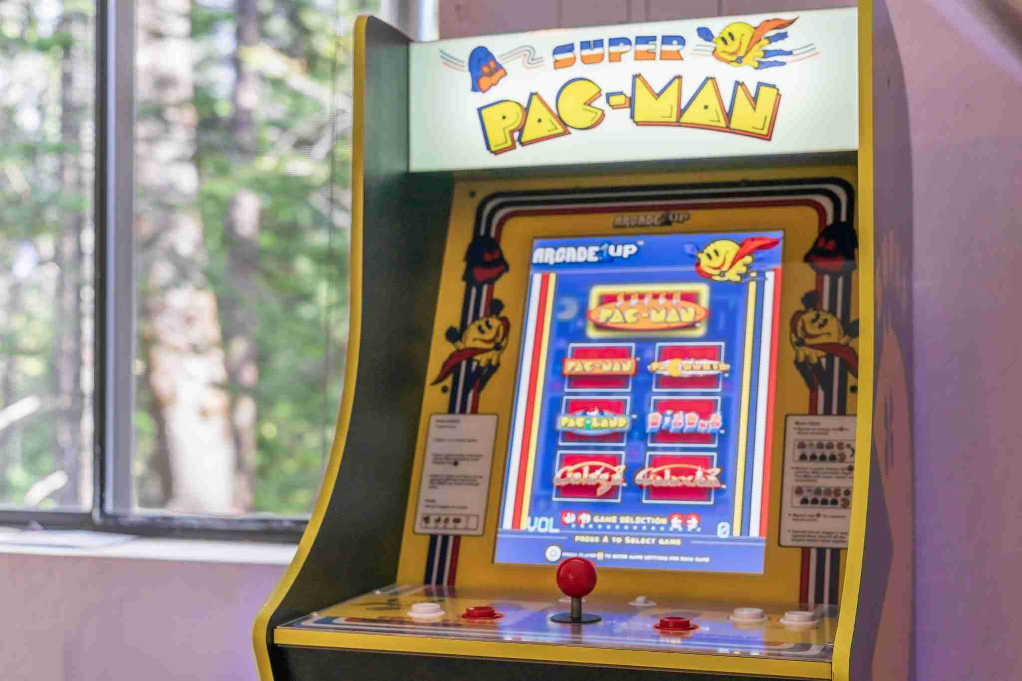 Arcade cabinet with "Super Pac-Man" near window, colorful design, joystick, buttons, game menu.