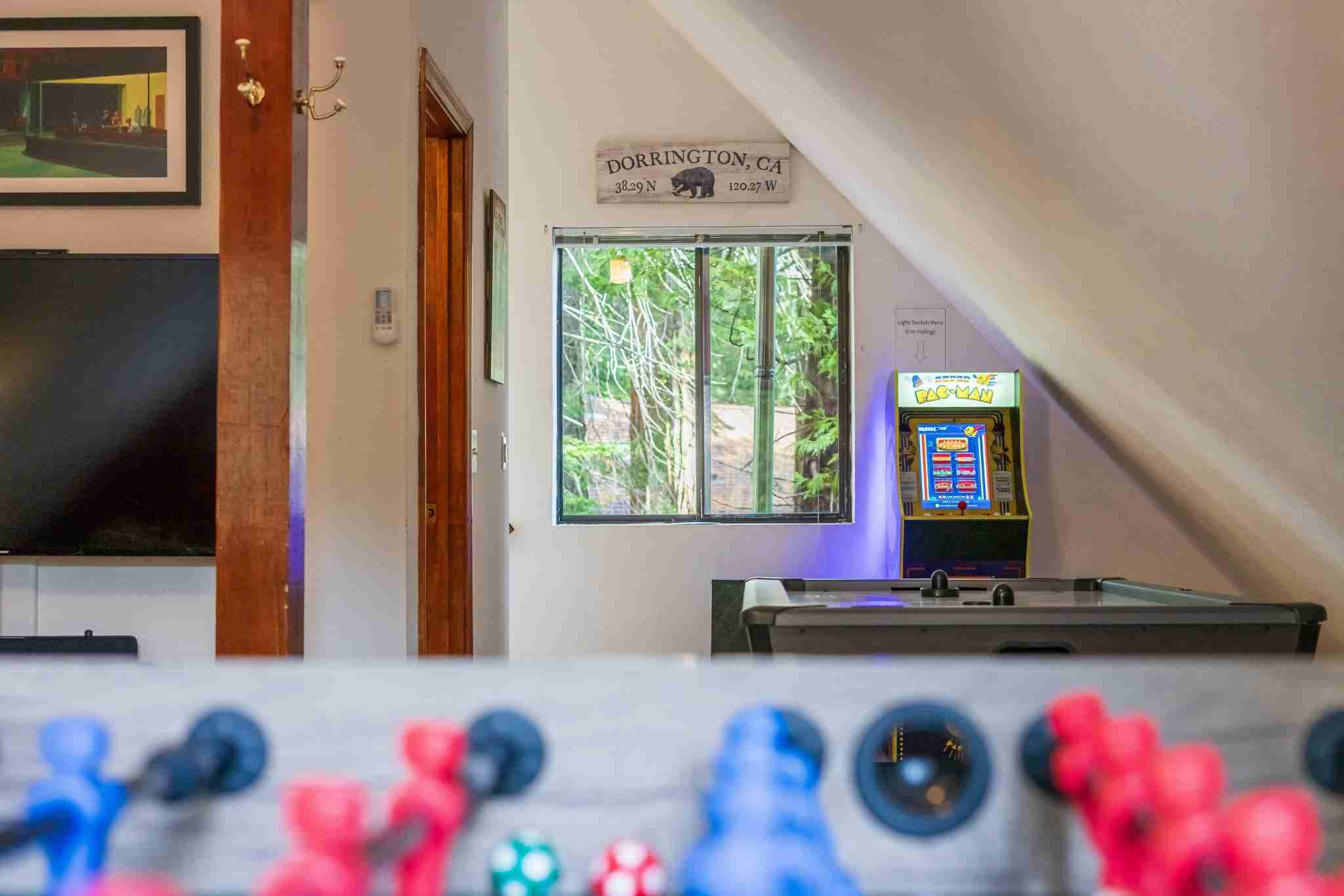 Recreation room with foosball, Pac-Man arcade, air hockey, window view, and location sign.