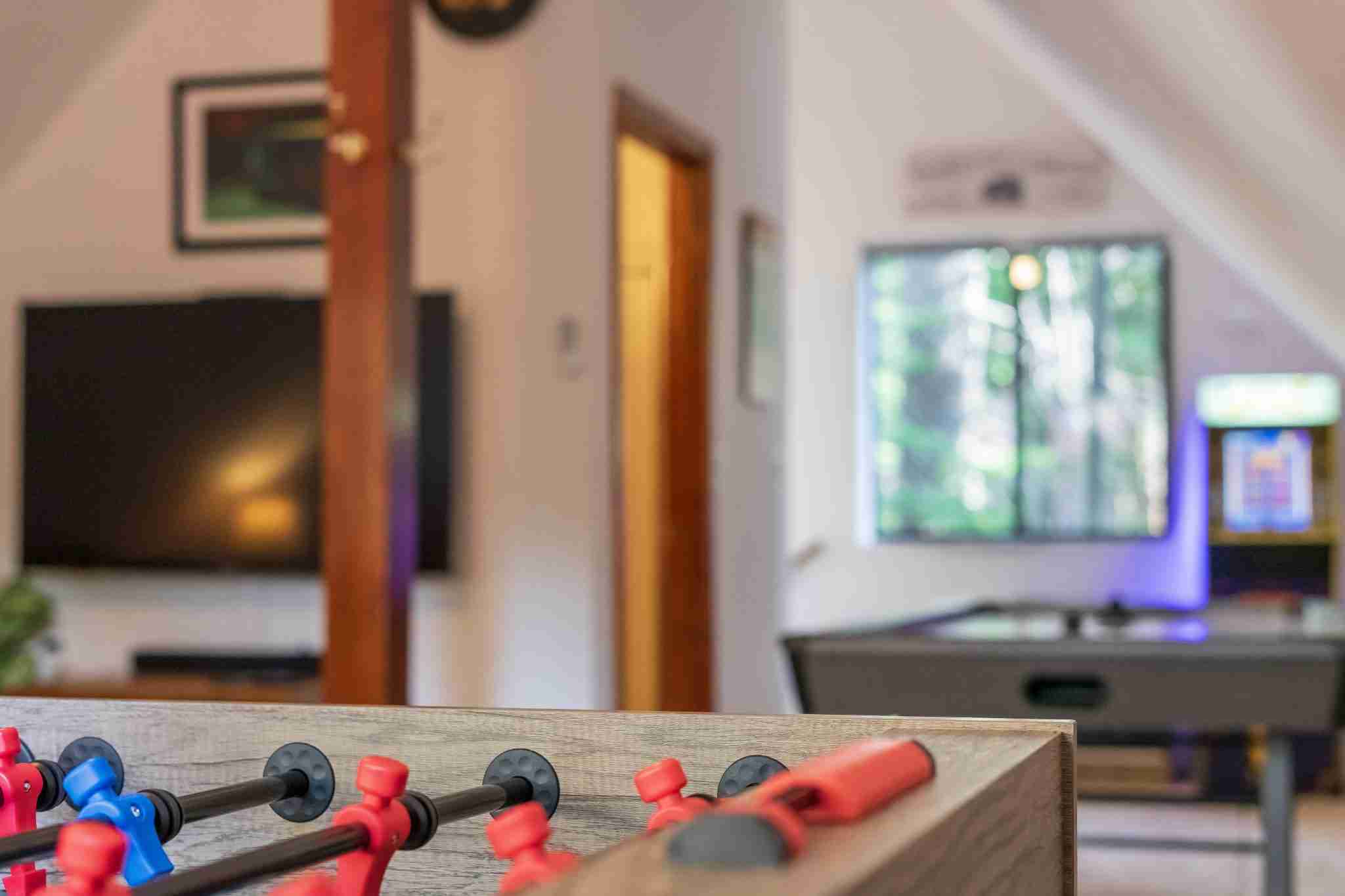 Indoor space with foosball table, TV, window view, and air hockey table in recreational area.