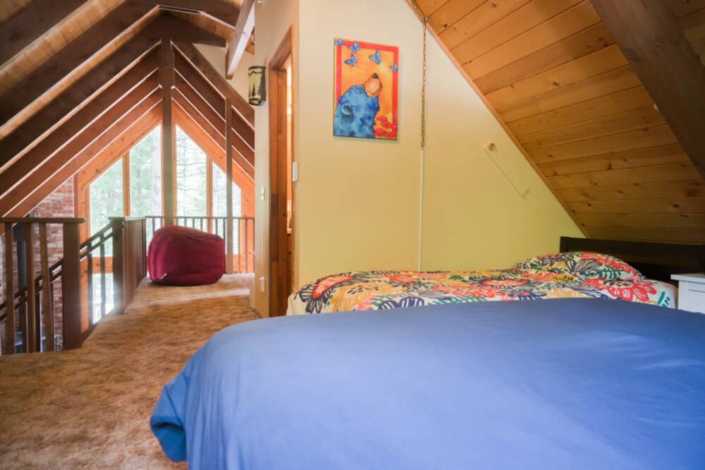 Dorrington Vacation Rental Cabins - A cozy attic bedroom with a colorful bedspread and a painting on the wall.
