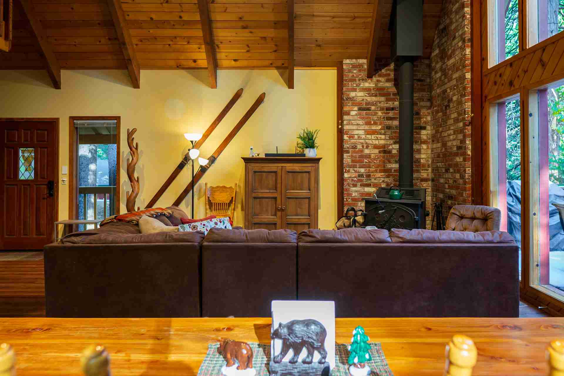 Cozy living room with brown sofa, wooden cabinet, stove, and rustic decor.