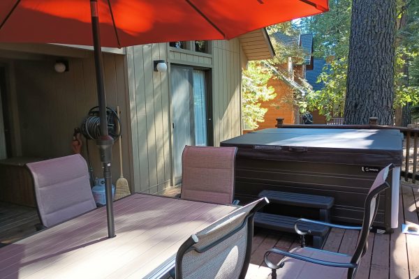 Dorrington Vacation Rental Cabins - A deck with a hot tub and chairs at Evergreen Pinecone Cottage.
